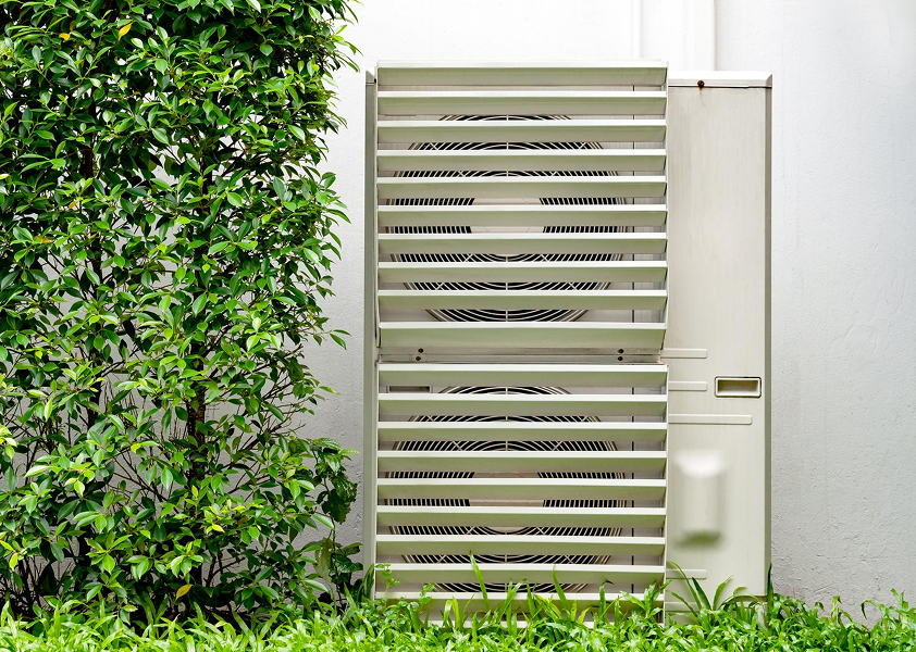 An outdoor AC unit with a tree nearby