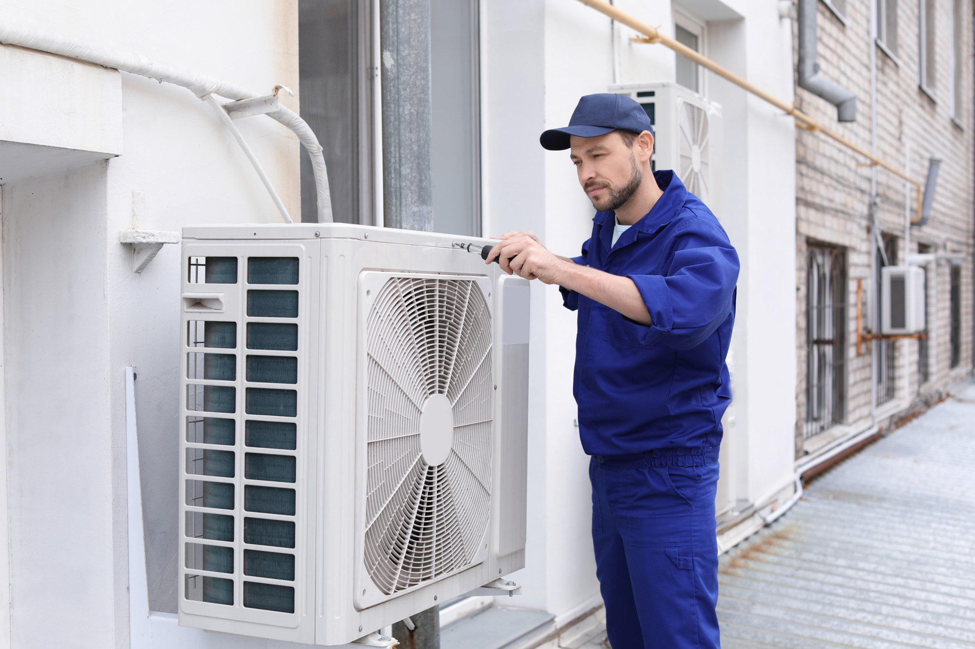 Male technician repairing air conditioner outdoors