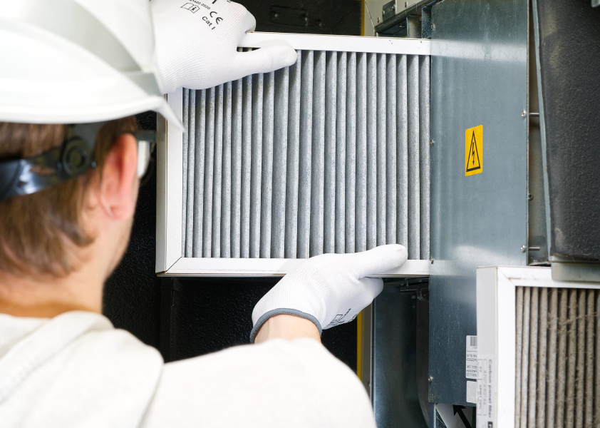 Person changing a furnace filter. Regular maintenance can help prevent an emergency furnace repair