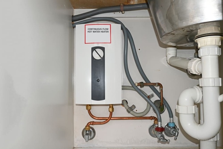 A tankless water heater attached to a basement wall