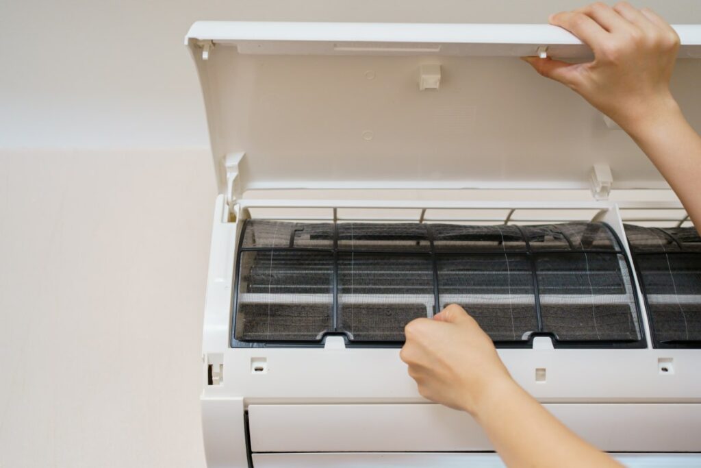 A woman cleans a dusty condo air conditioner 