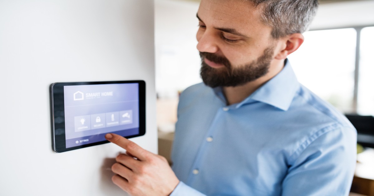 A man adjusts his HVAC zoning system temperature on a thermostat