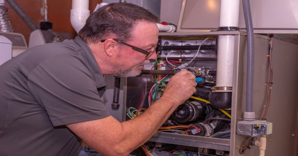 A repairman working on a leaking furnace