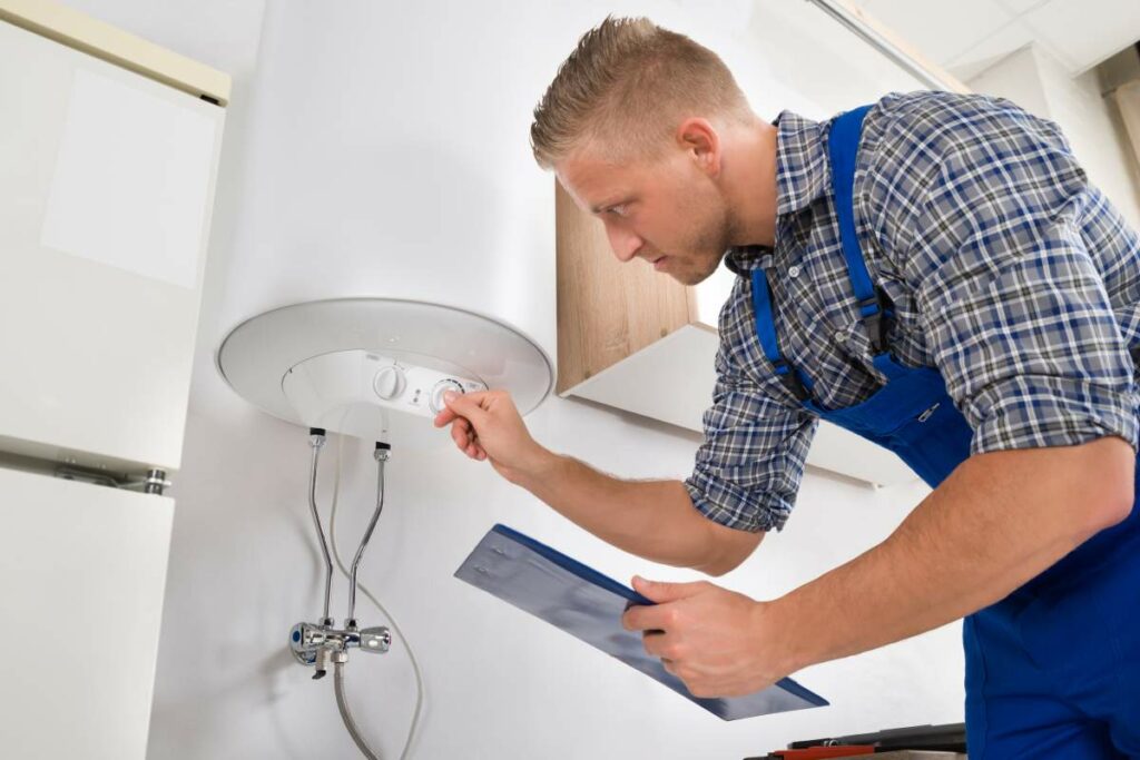 Male worker with clipboard adjusting temperature of water heater