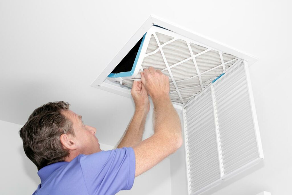 man taking out a dirty air filter from a home ceiling air return vent